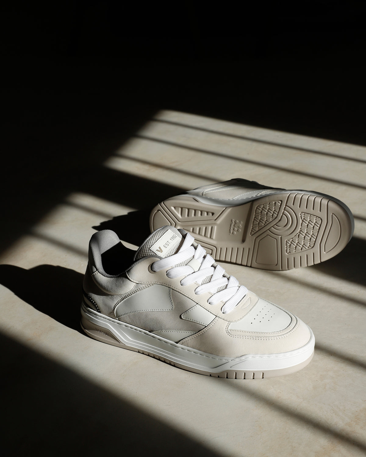 Foto van beige VIA VAI heren sneakers Jay Randy, op betonnen vloer in zonlicht.