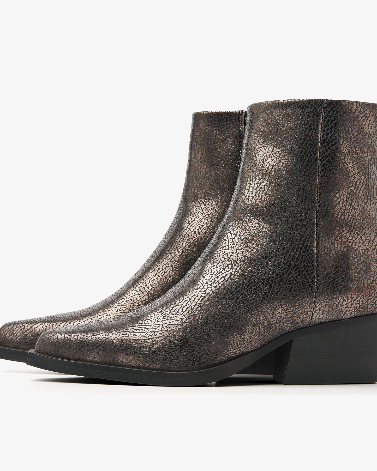 De VIA VAI Do Cassidy is een paar metallic enkellaarsjes met lage blokhakken en spitse tenen, met een gedurfde metallic afwerking op een effen witte achtergrond.