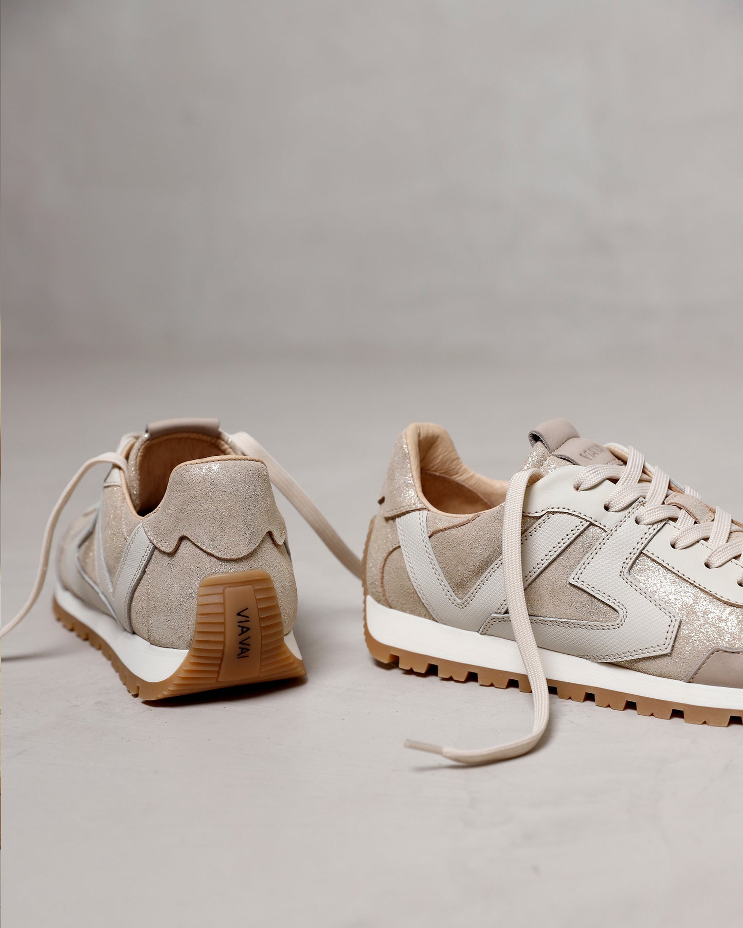 VIA VAI Scott Kenzie gouden sneakers dames, staand op een lichte betonnen ondergrond.