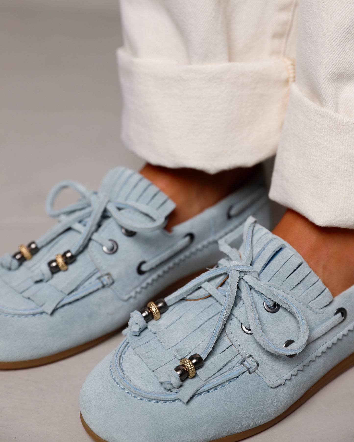 Detailfoto van suède blauwe VIA VAI dames loafers June Loua, aan de voet gedragen met witte jeans.